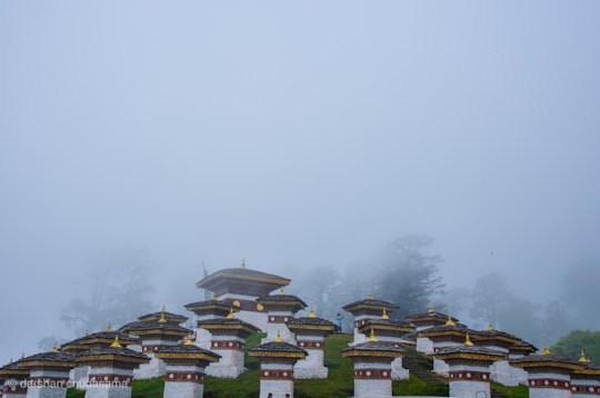 white and green temple under white sky during daytime in Dochula Bhutan