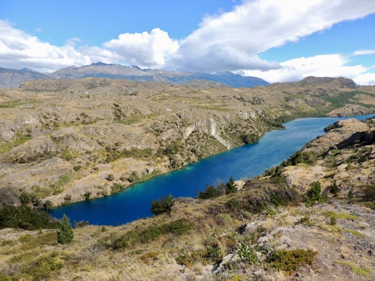 blue lake surrounded by green grass and trees under blue sky and white clouds during daytime in Chile Chico Chile