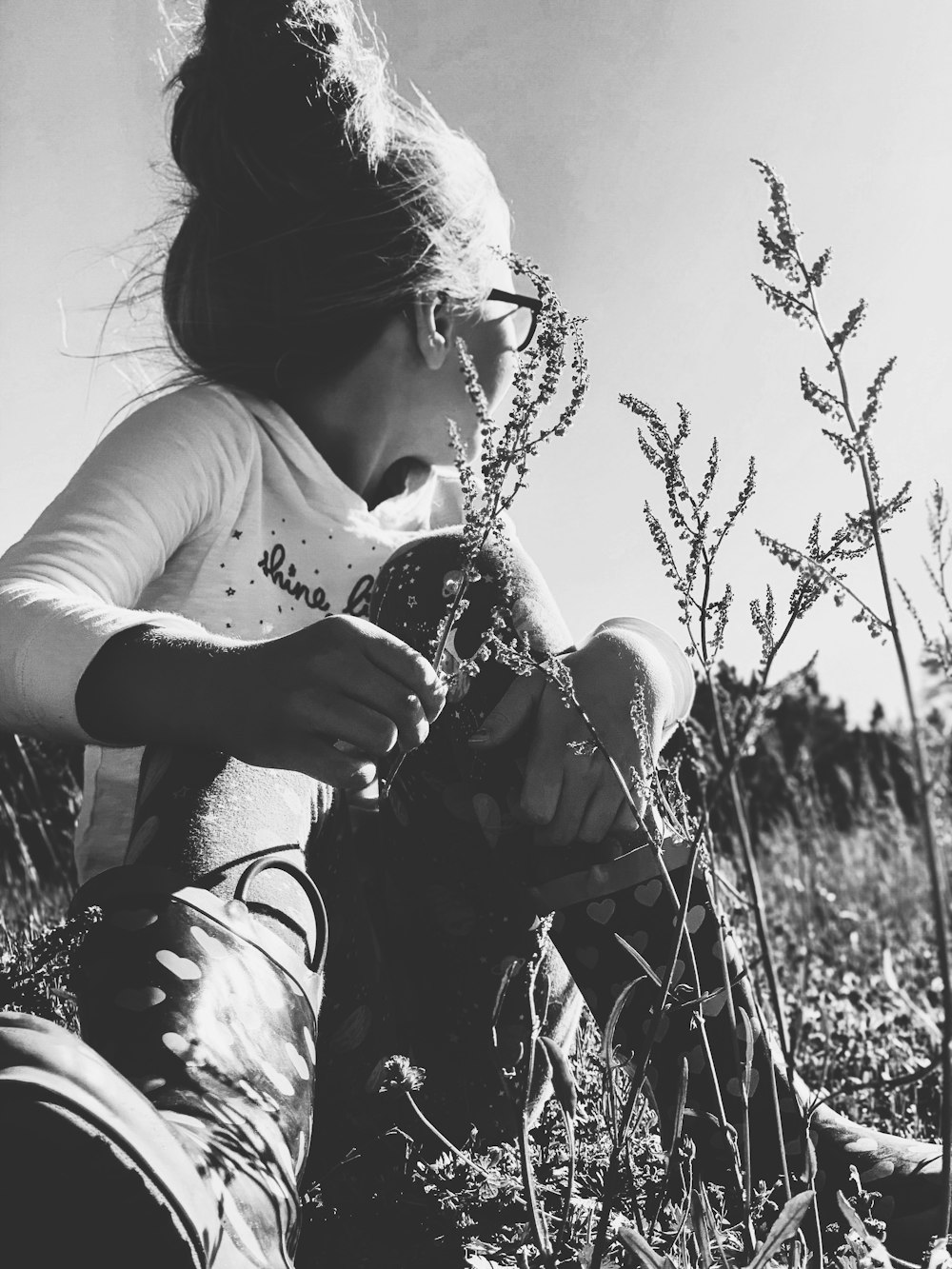 woman in white t-shirt and black pants sitting on grass field