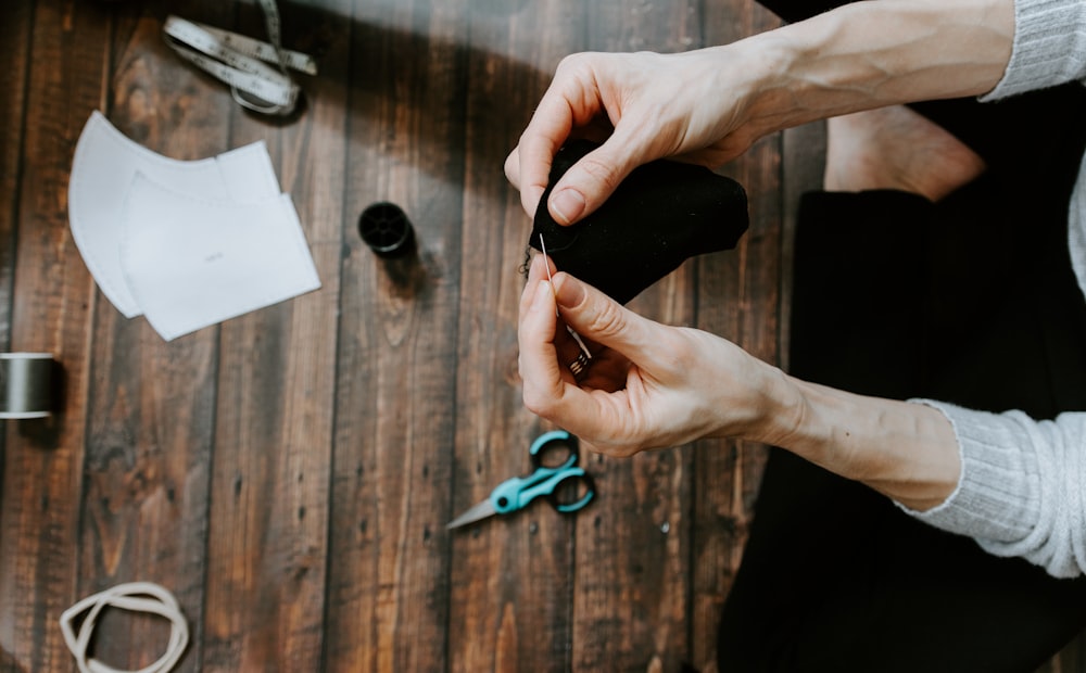 person holding blue and black scissors