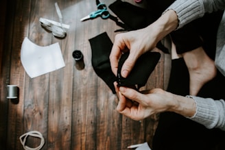 person holding black textile on brown wooden table