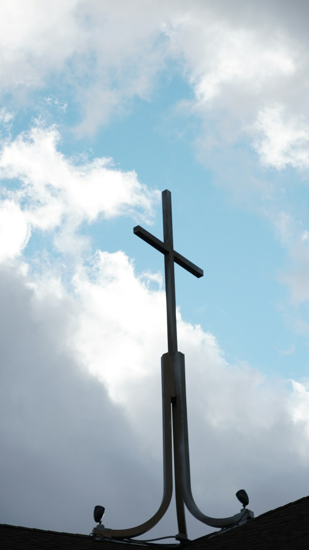 a cross on top of a building with clouds in the background