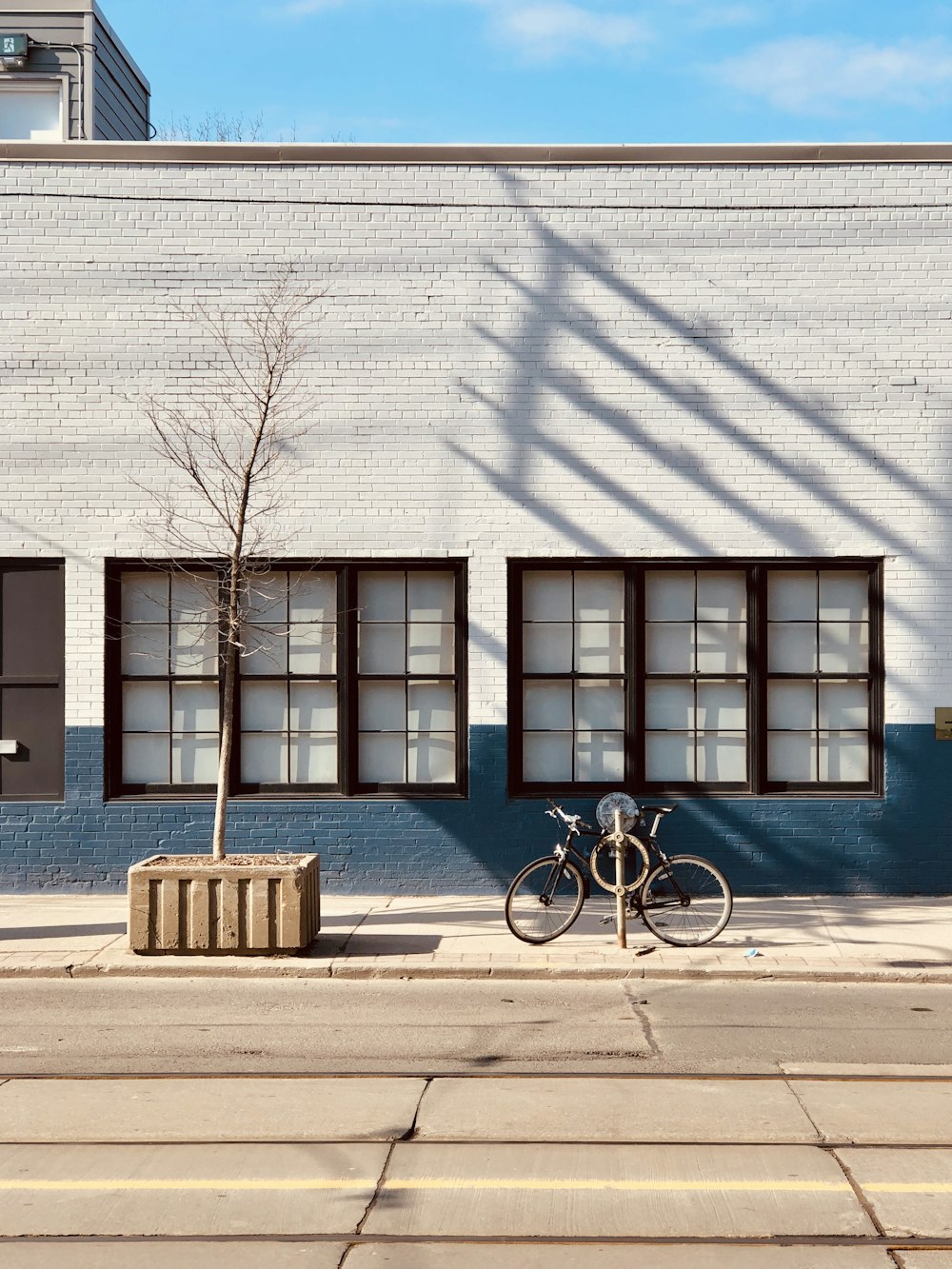black bicycle parked beside blue concrete building