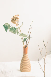 Close-up of natural handmade rustic vase with dried flowers on a minimalist cream background