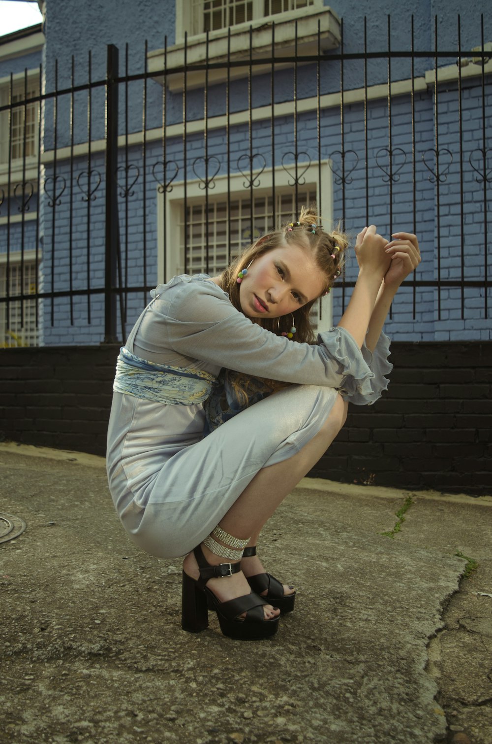 woman in blue long sleeve shirt and gray pants sitting on brown concrete floor during daytime