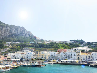 A vibrant coastal town with colorful fishing boats and historic ramparts under a bright blue sky.