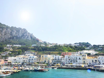 A vibrant coastal town with colorful fishing boats and historic ramparts under a bright blue sky.