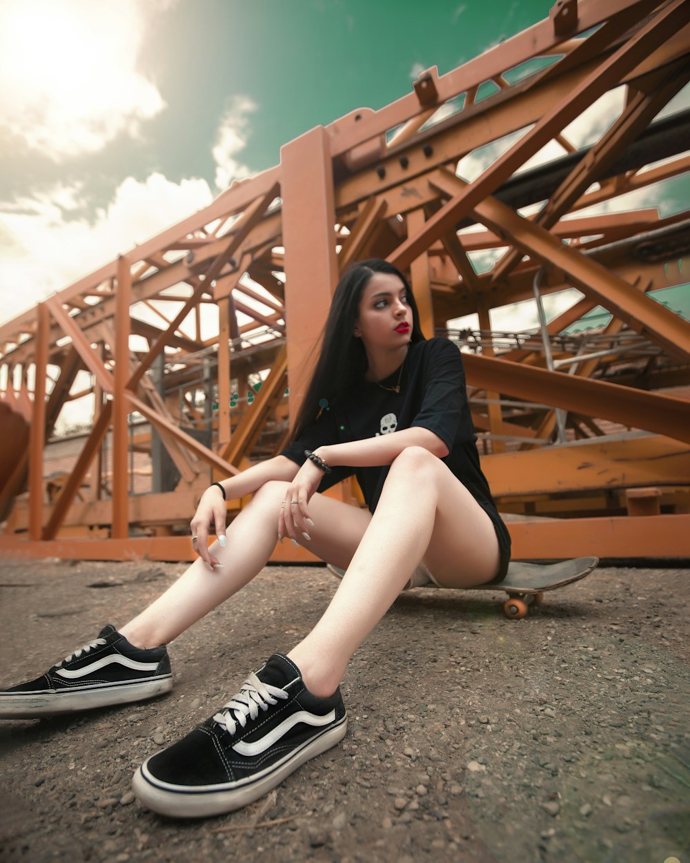 woman in black and white nike sneakers sitting on brown wooden bridge during daytime
