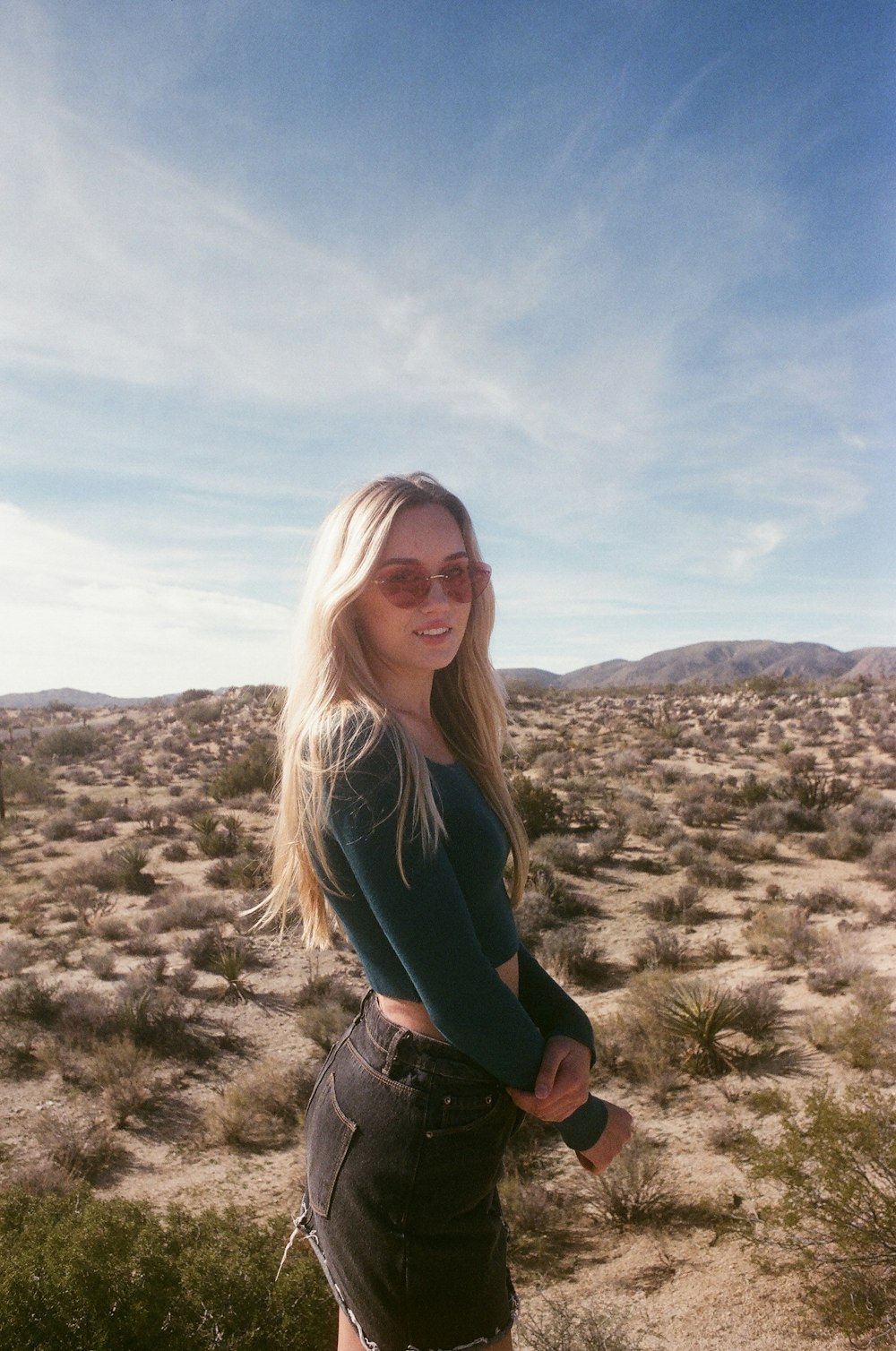 woman in black long sleeve shirt and gray pants wearing black sunglasses standing on green grass