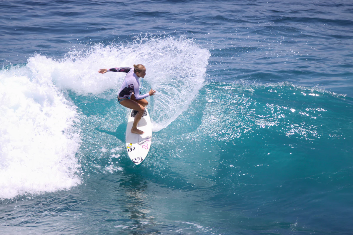 A woman carving a hard turn through clear turquoise water, throwing up a wall of spray