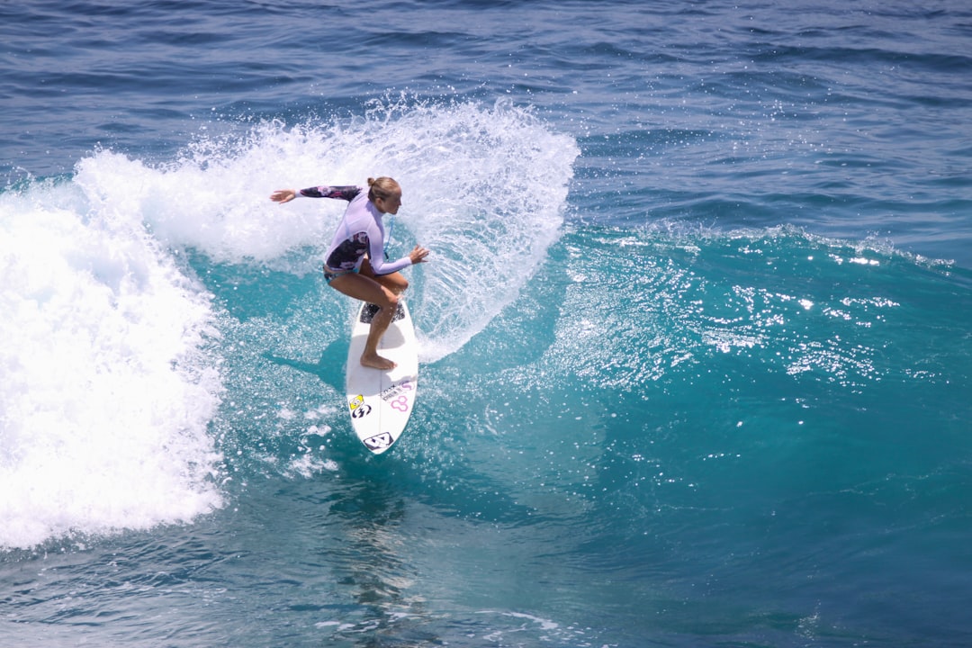 woman in black bikini surfing on sea waves during daytime