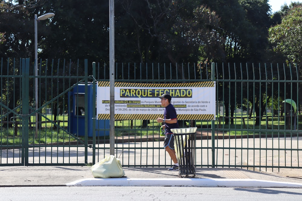 uomo in polo gialla e jeans blu in piedi sul marciapiede durante il giorno