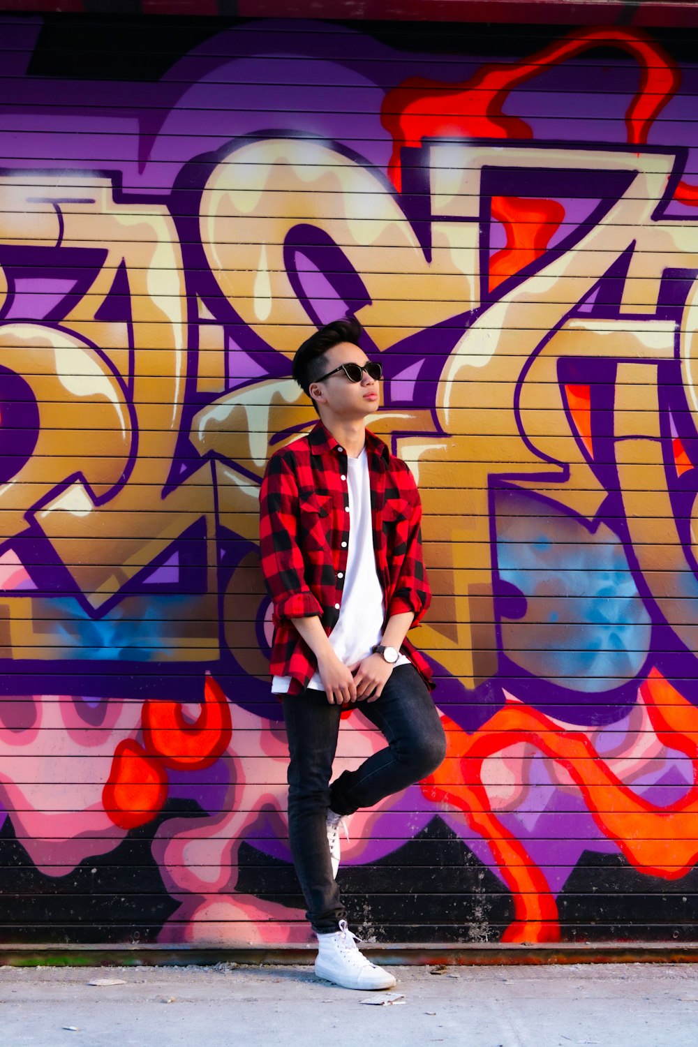 woman in red and black jacket and black pants standing on purple and yellow wall