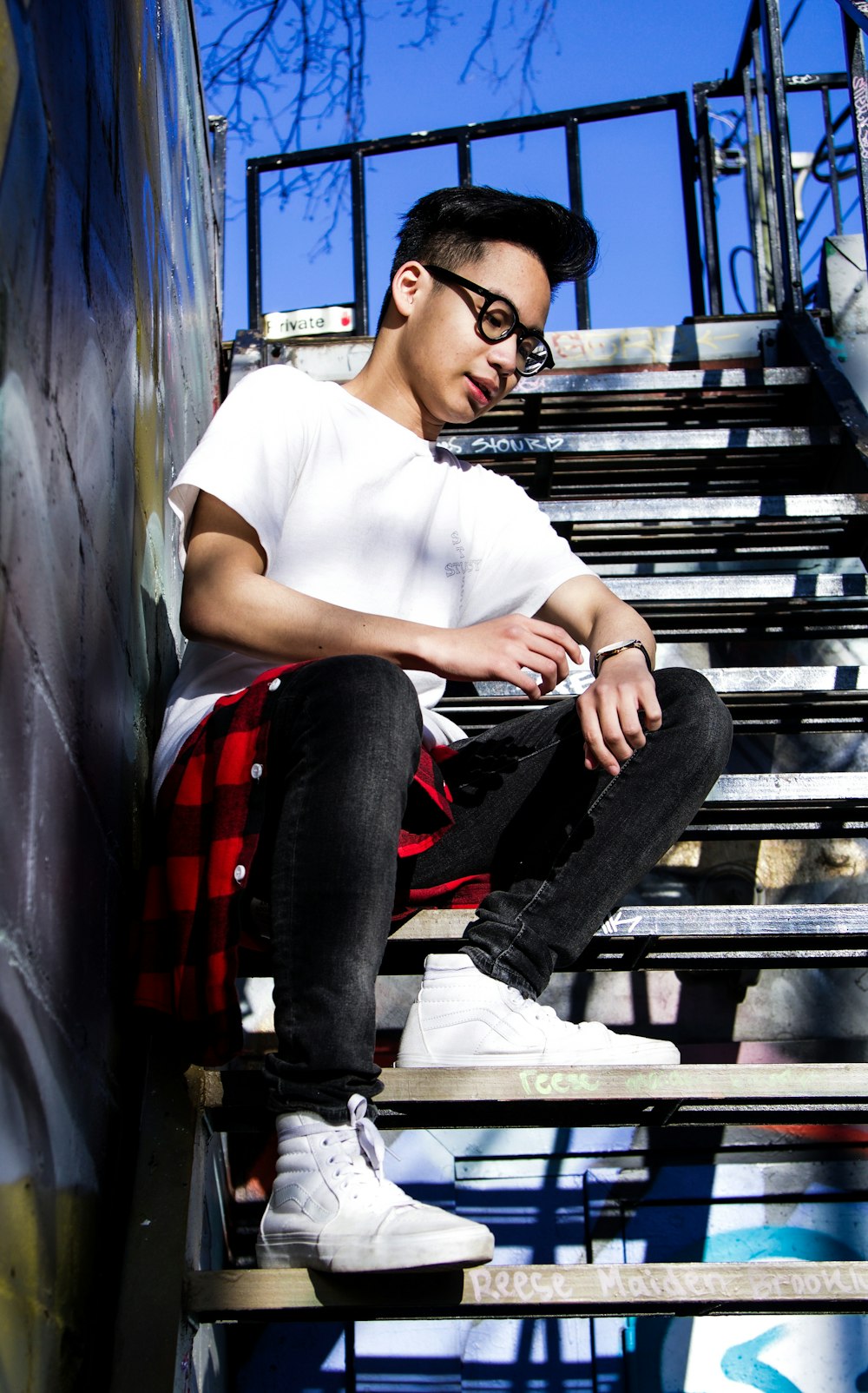 man in white crew neck t-shirt and black denim jeans sitting on black metal bench