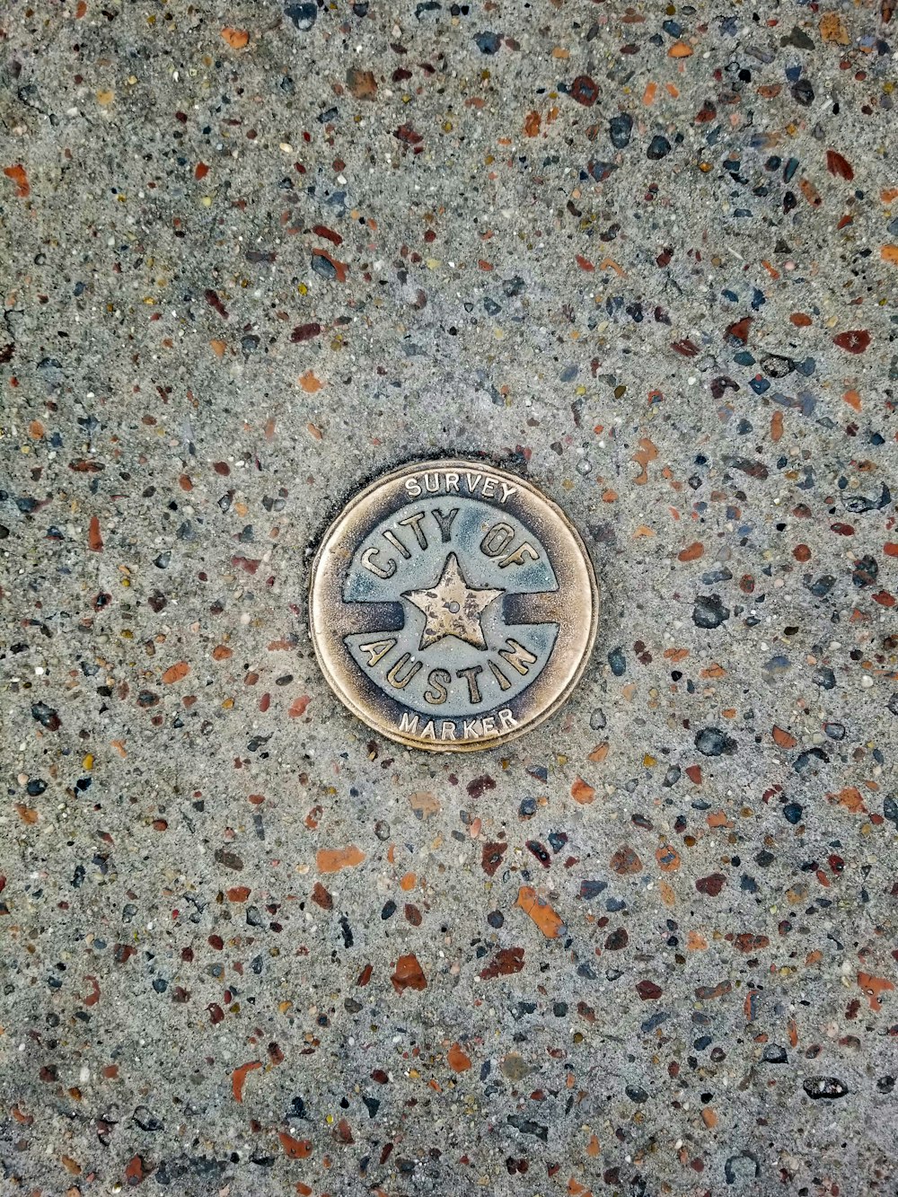 silver round coin on gray and brown surface