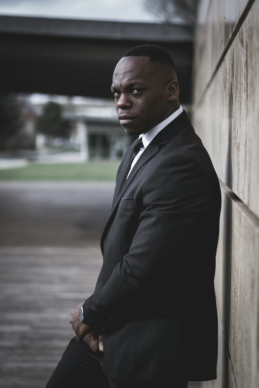 a man in a suit leaning against a wall