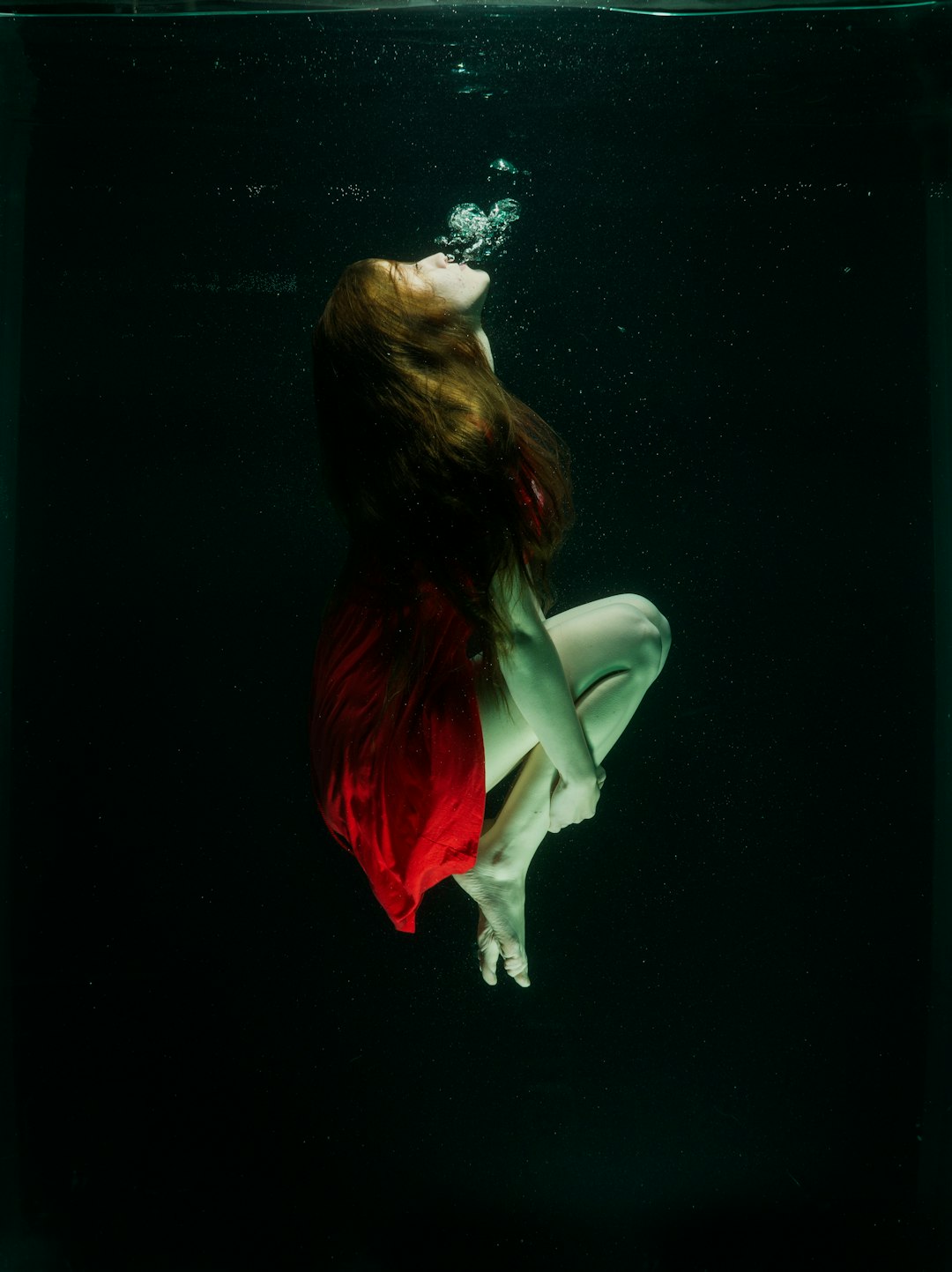 woman in red dress lying on black surface