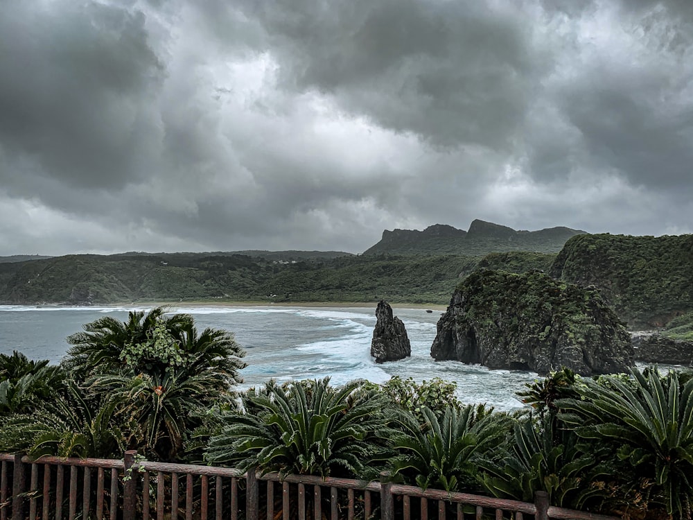 green mountain beside body of water under cloudy sky during daytime