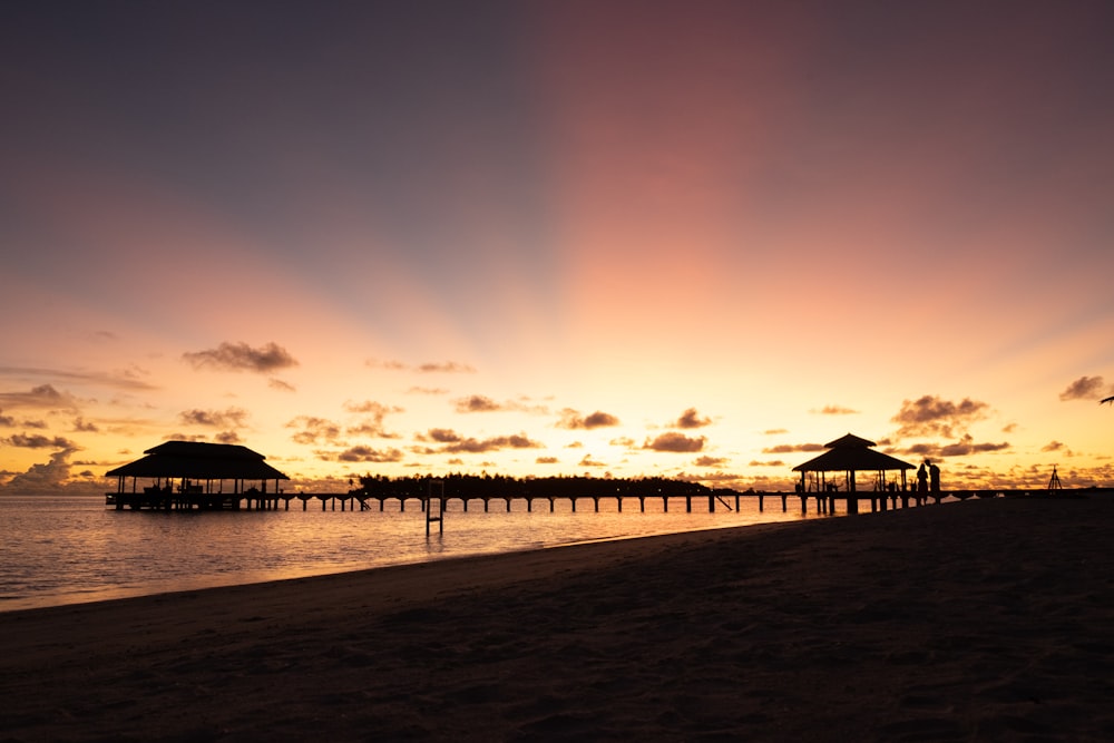 silhouette of dock on sea during sunset