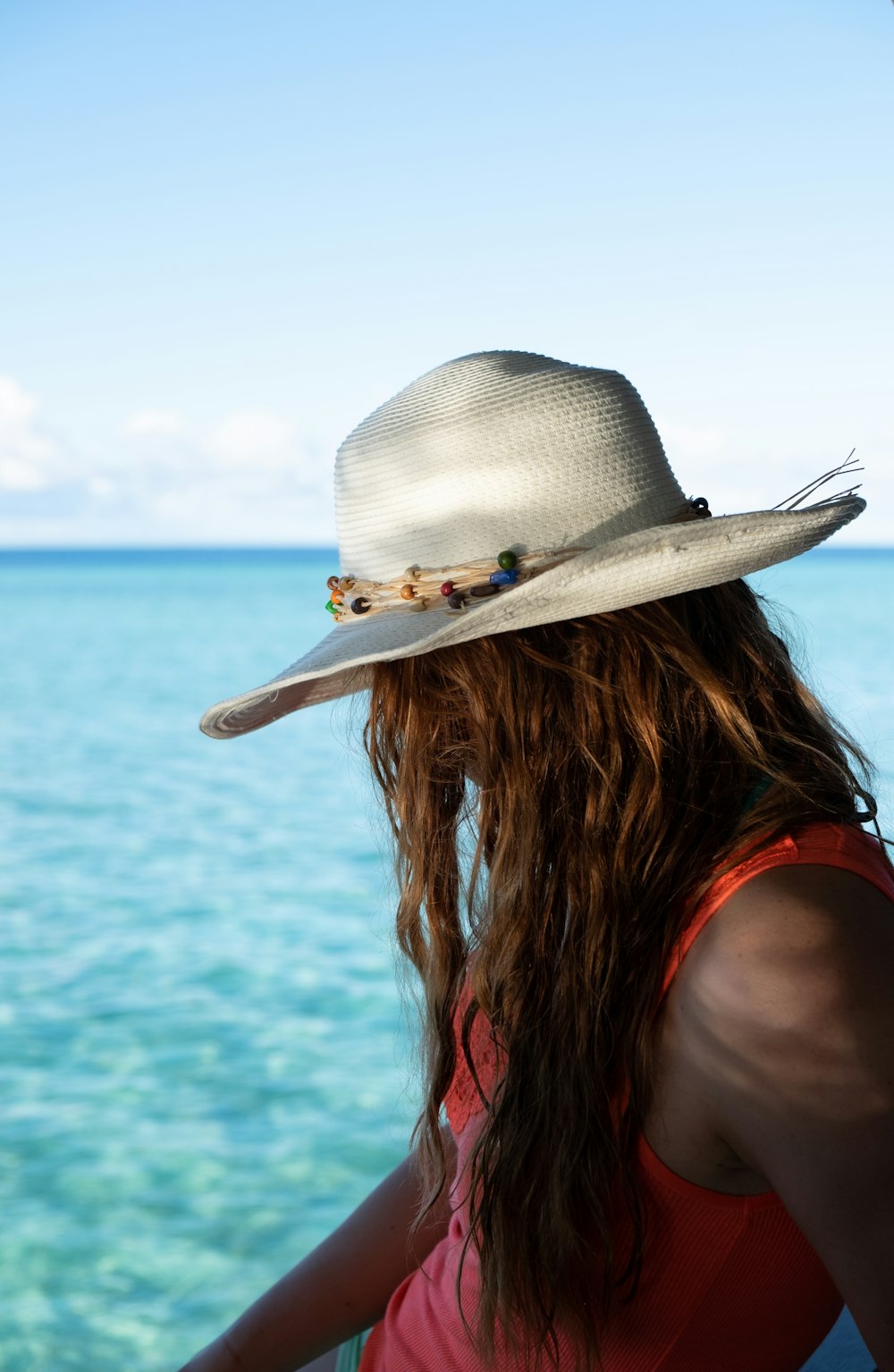 woman in white sun hat standing on beach during daytime