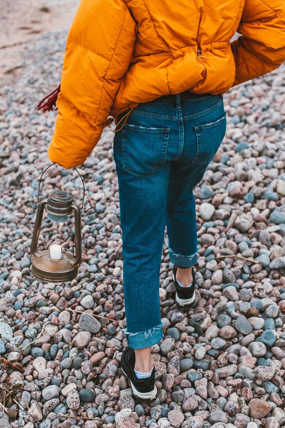 person in yellow jacket and blue denim jeans standing beside silver and black stand