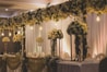 A beautifully decorated wedding reception with soft neutral tones and refined floral accents under warm lighting.