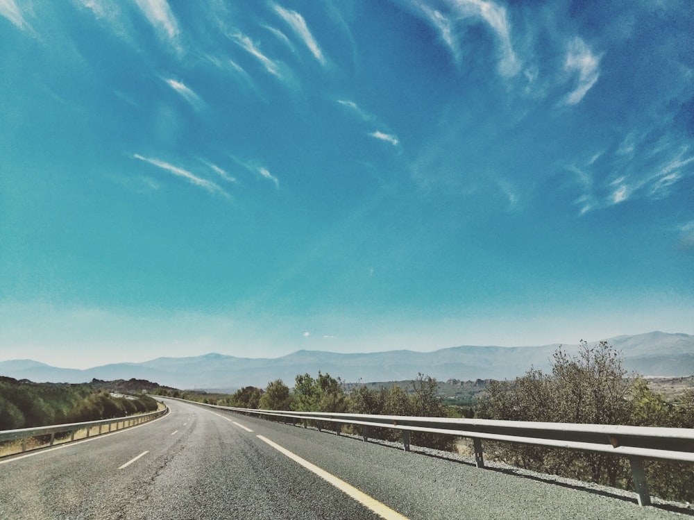 gray concrete road under blue sky during daytime