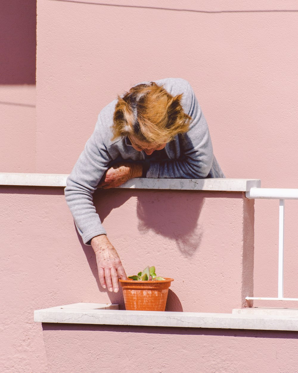 woman in gray long sleeve shirt sitting on white concrete bench