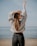 woman in white sweater and blue denim jeans standing on beach shore during daytime