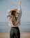 woman in white sweater and blue denim jeans standing on beach shore during daytime