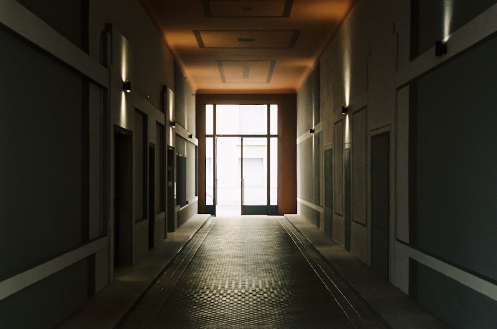 Pasillo de un edificio que conduce a una puerta acristalada iluminada