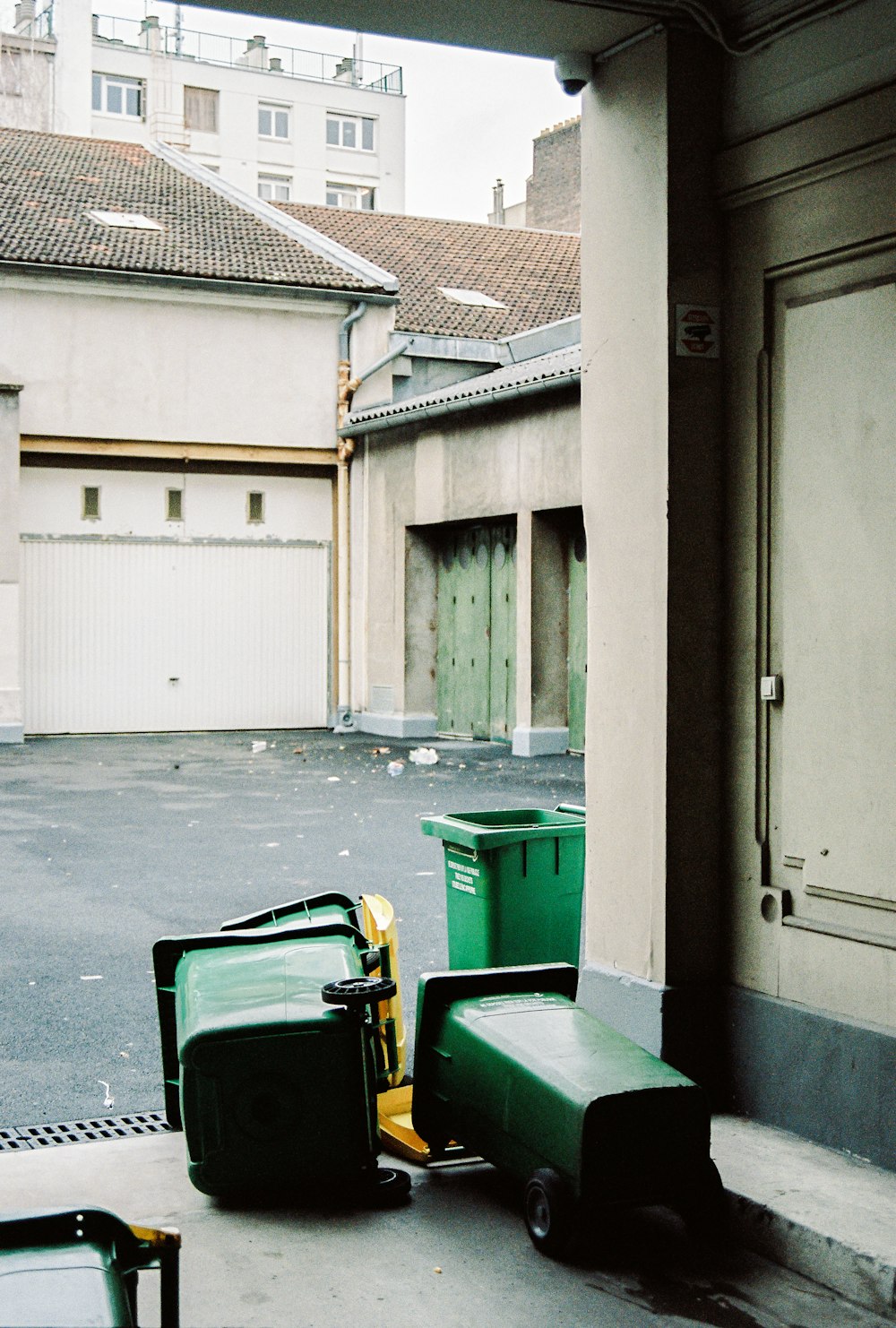 green trash bin beside white wooden door
