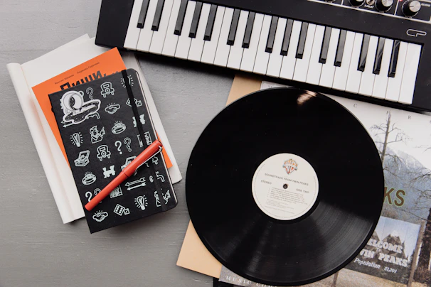 Y’man Dog writing lyrics in a notebook, surrounded by vinyl records and music gear.