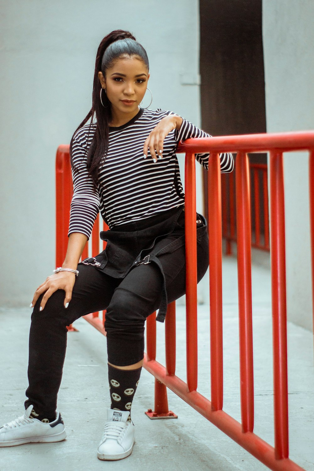 woman in black and white striped long sleeve shirt and black pants sitting on red metal