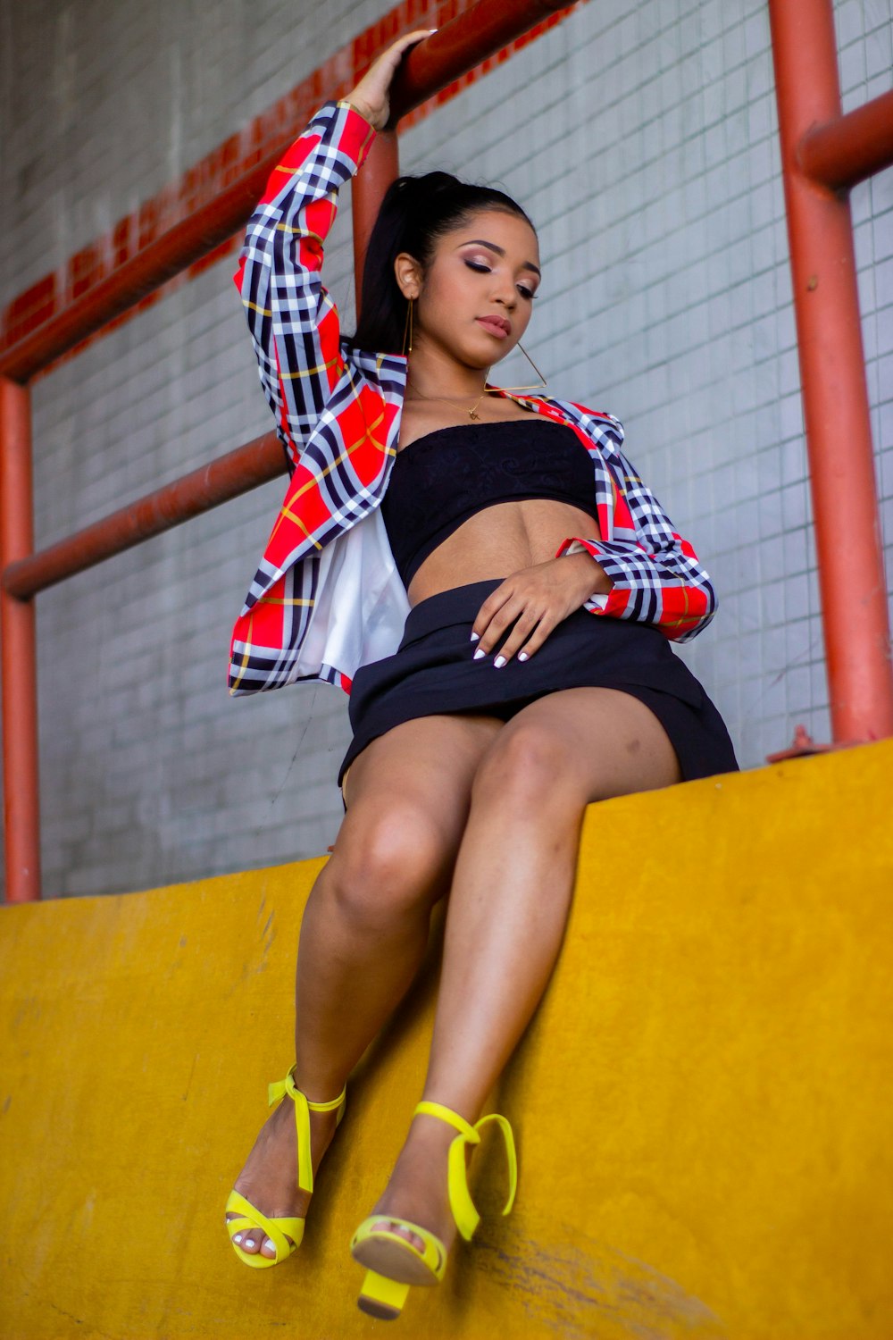 woman in red and white plaid shirt and black skirt sitting on yellow chair