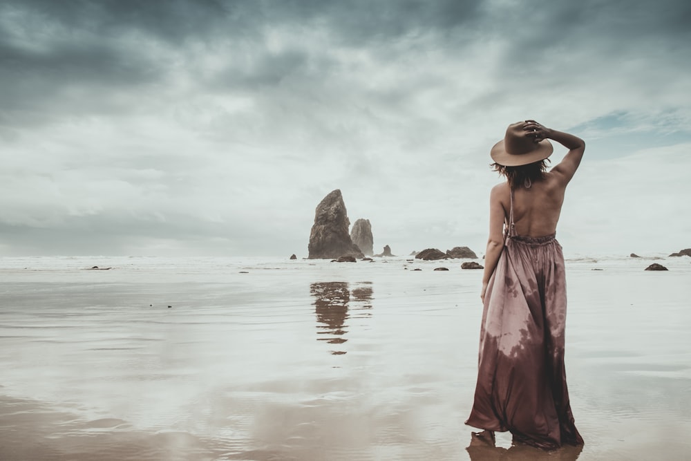 woman in red dress standing on seashore during daytime