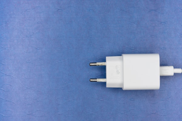a white computer charging plug against a lightly-patterned violet background