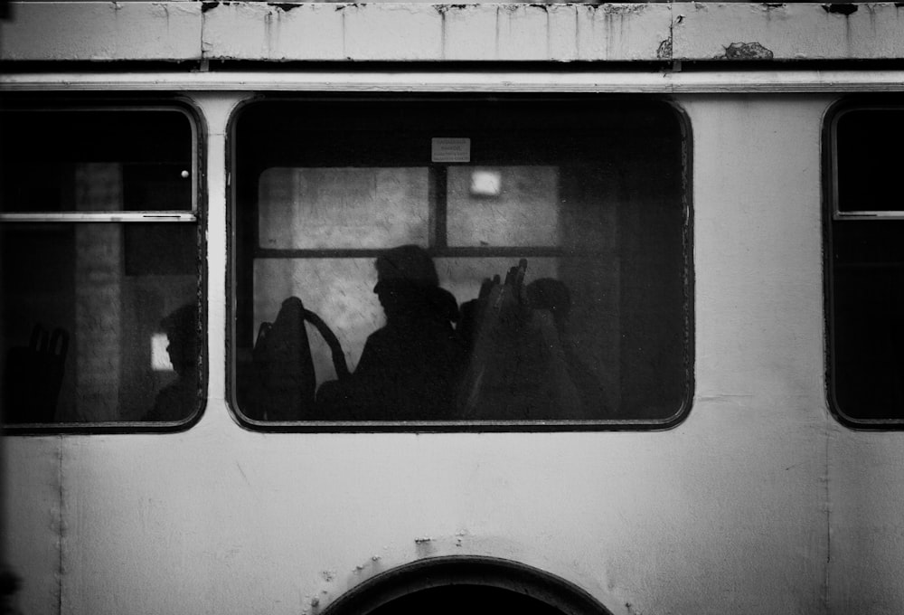 man in black jacket standing in front of white and blue bus