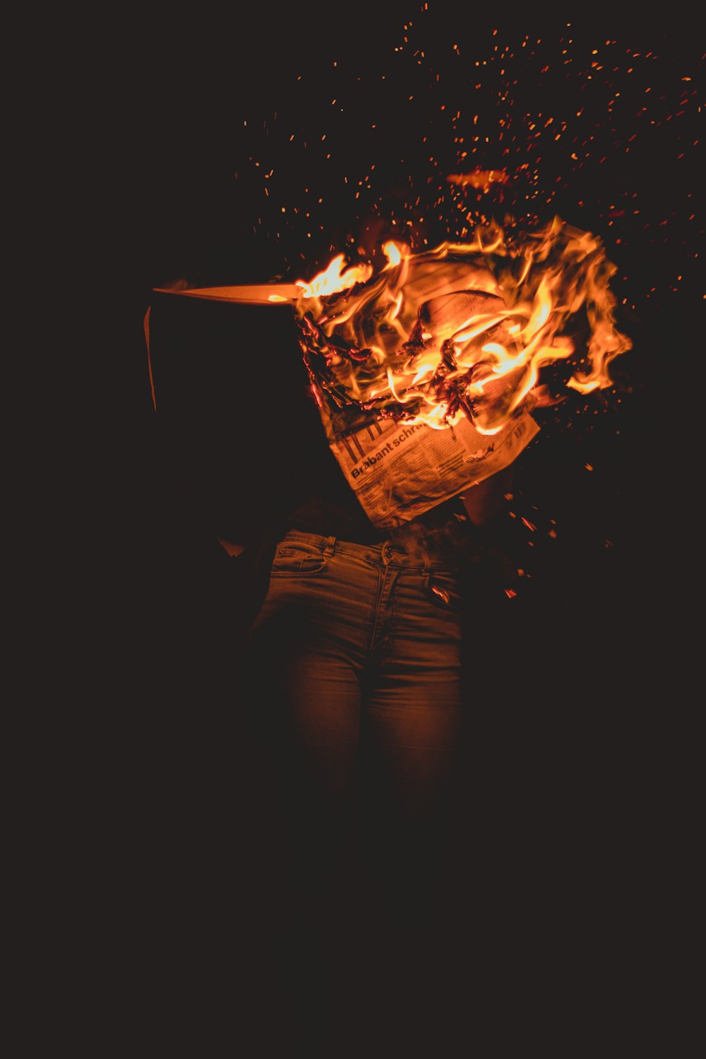 person in blue denim jeans standing in front of fire