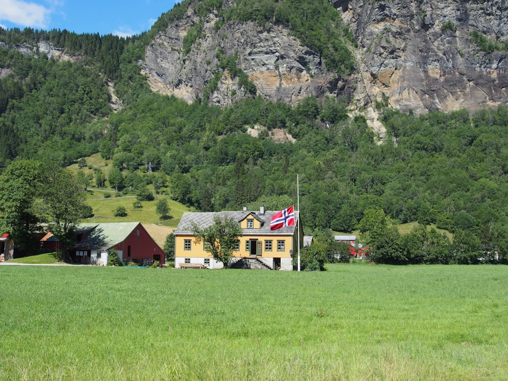 Weißes und braunes Haus auf grünem Grasfeld in der Nähe von Berg tagsüber