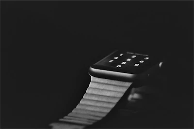 Close-up of a modern smartwatch with a glowing neon green interface against a dark background.