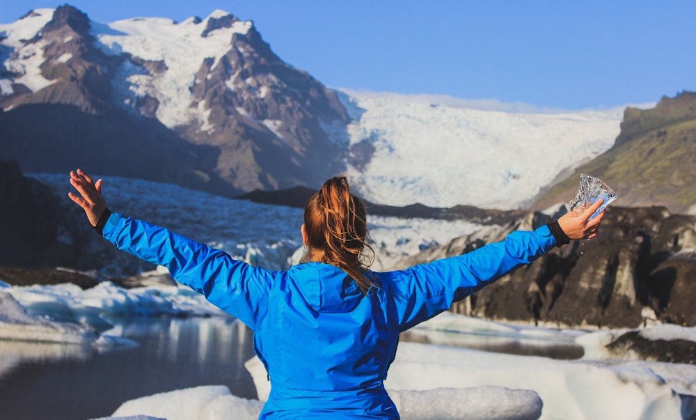 Mujer en chaqueta azul de pie en el suelo cubierto de nieve durante el día