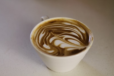 A sleek coffee cup with latte art placed on a clean white and brown counter at Padaria da Batalha.
