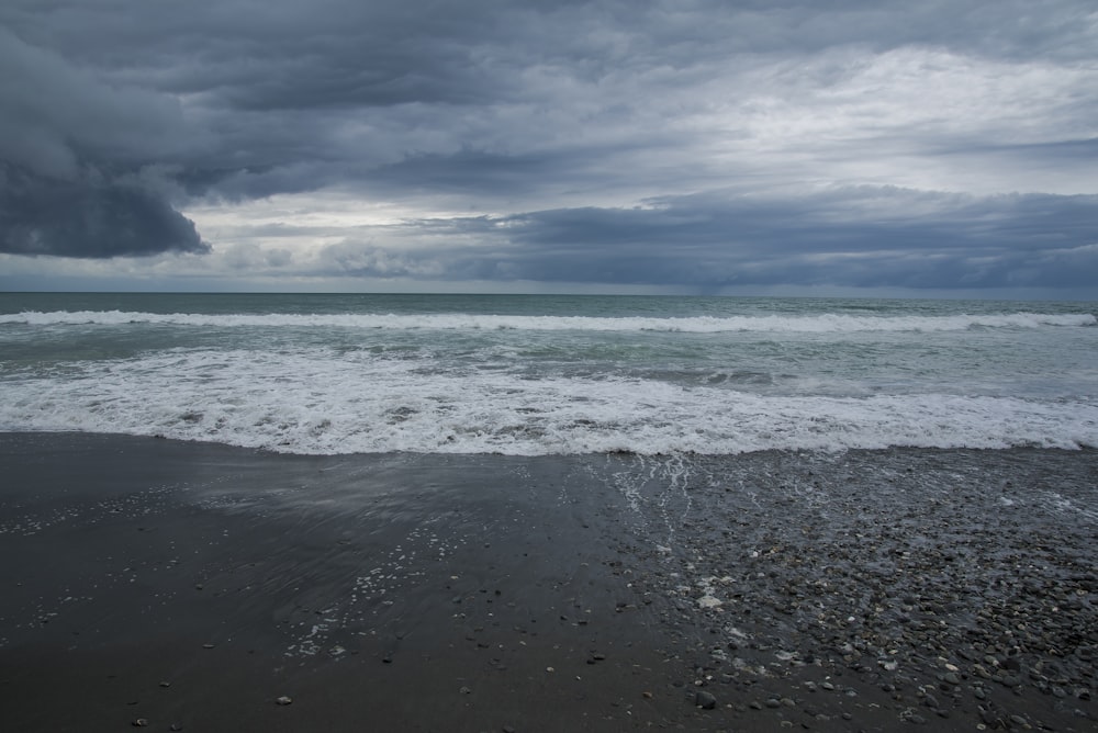 sea waves crashing on shore under blue and white cloudy sky during daytime