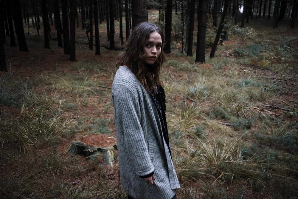 woman in gray sweater standing on green grass field during daytime