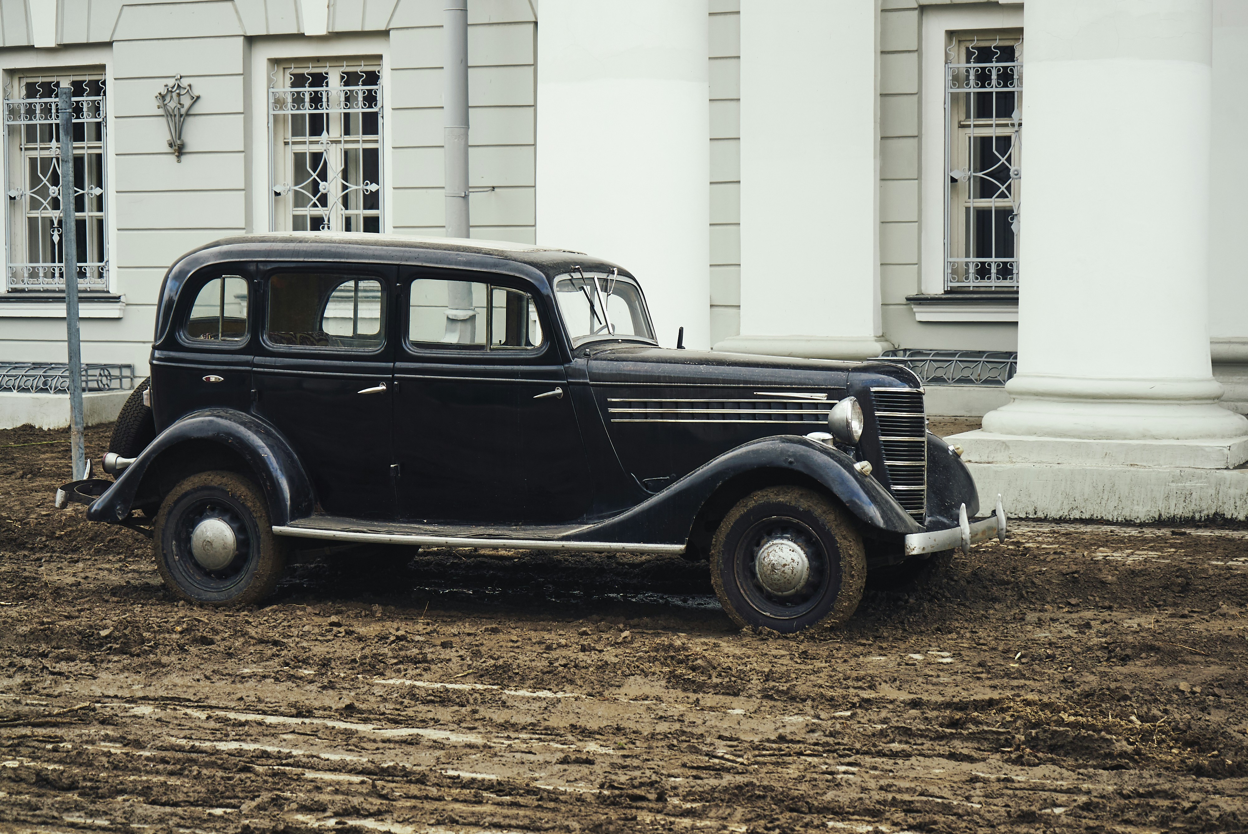 Black vintage car parked beside white building