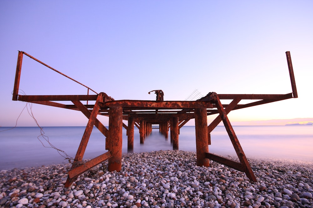 brown wooden ladder on gray and white pebbles near body of water during daytime