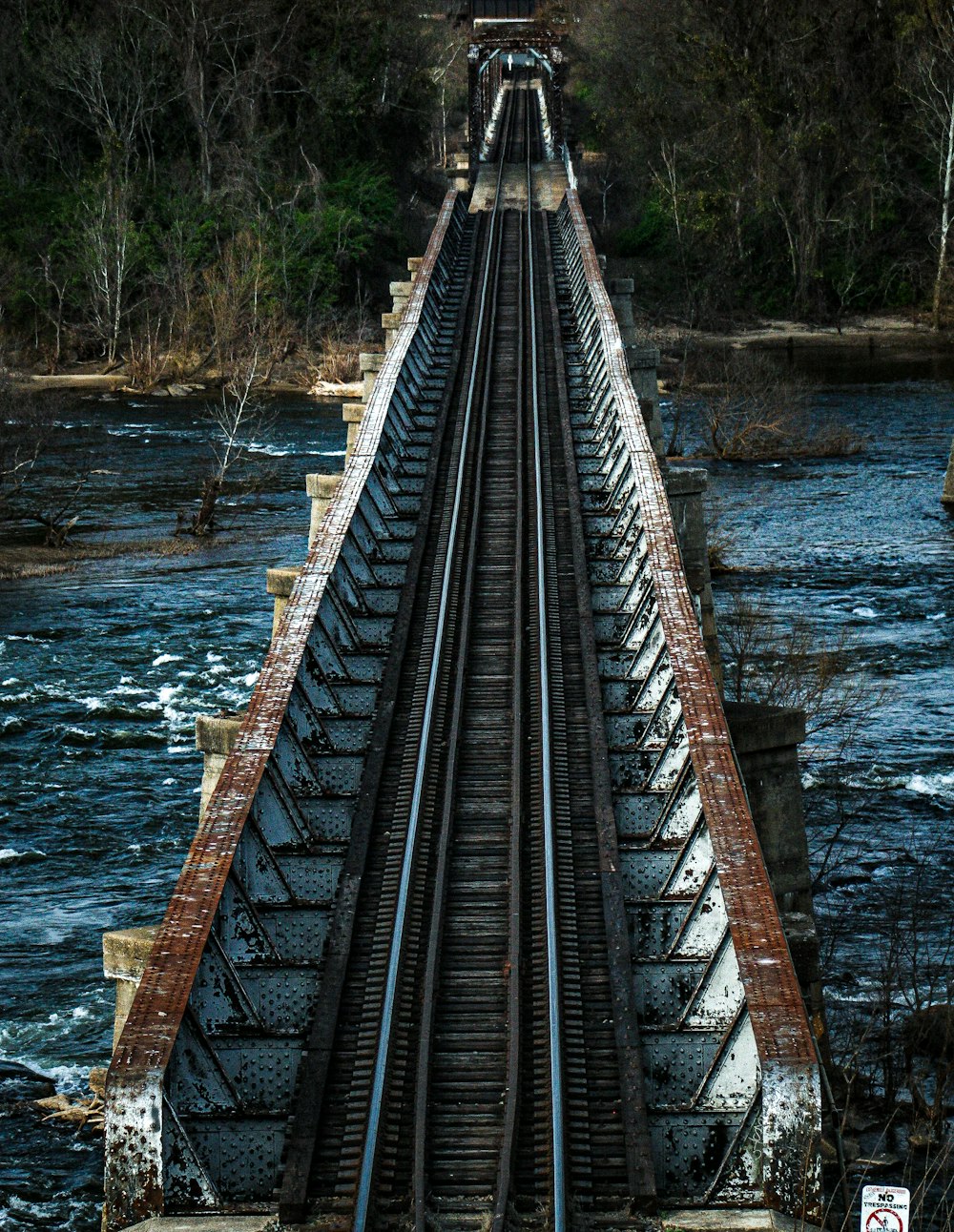 gray metal train rail near body of water during daytime
