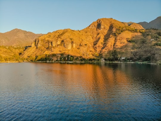 brown mountain beside body of water during daytime in Lake Atitlán Guatemala