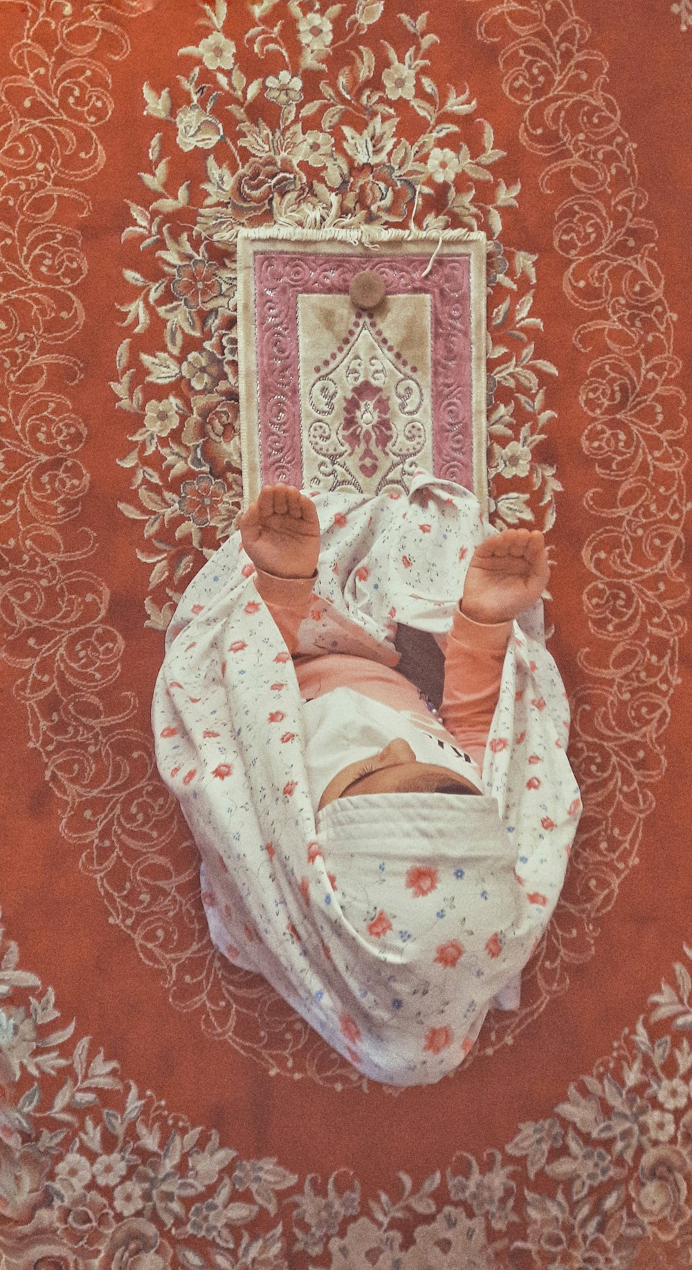 woman in white and blue floral dress lying on red and white floral textile